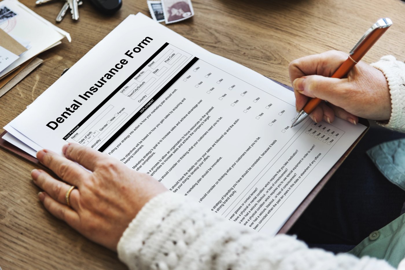 A person filling out a dental insurance form on a clipboard