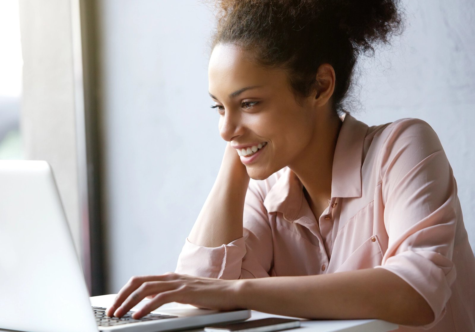 A woman smiling while using a laptop computer